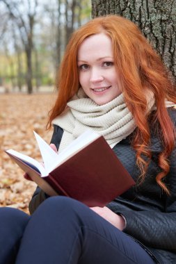 Kızıl saçlı kız Güz sezon Şehir Parkı, kitap okumak
