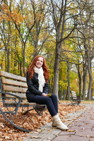 Redhead girl sitting on a bench in city park, autumn season — Stock Photo, Image