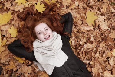 Kızıl saçlı kız yatan bırakır ve Şehir Parkı içinde Güz sezon wink