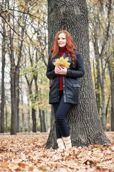 Rusovláska dívka s listy v městském parku, podzim — Stock fotografie