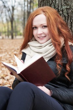 Kızıl saçlı kız Güz sezon Şehir Parkı, kitap okumak