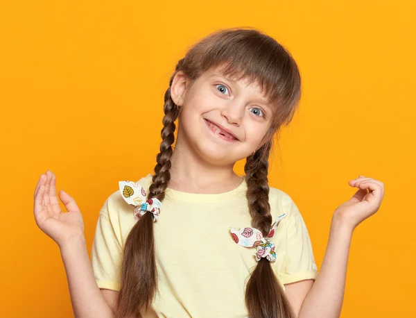 Mädchenporträt mit verlorenen Zähnen, Studioaufnahme auf gelbem Hintergrund — Stockfoto