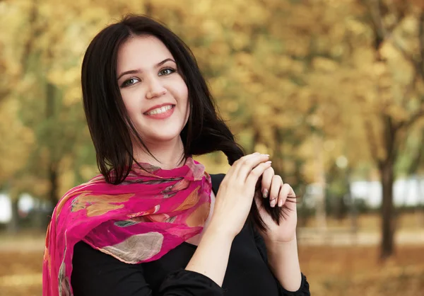 Beautiful girl in black dress and red scarf in yellow city park, fall season — Stock Photo, Image