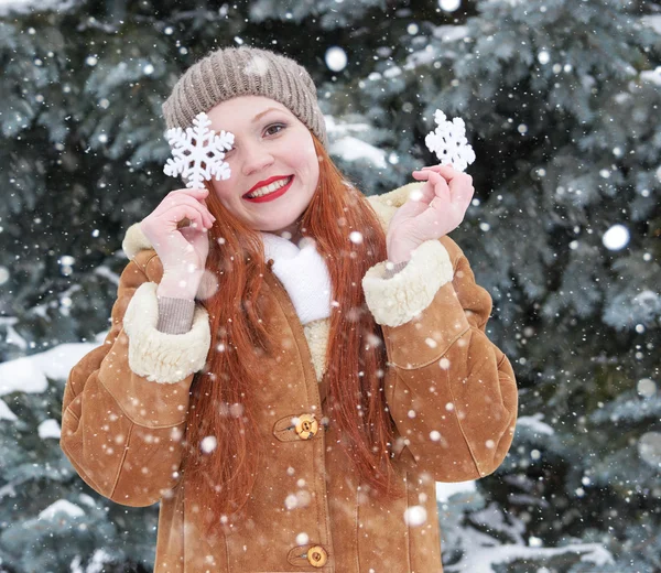 在冬天室外，下雪天气，显示大雪花玩具的女孩画像. — 图库照片