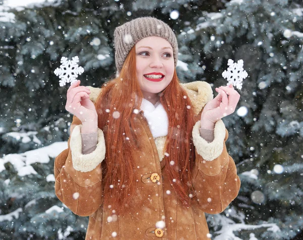 Retrato de niña en invierno al aire libre, clima nevado, mostrando gran juguete de copo de nieve . — Foto de Stock