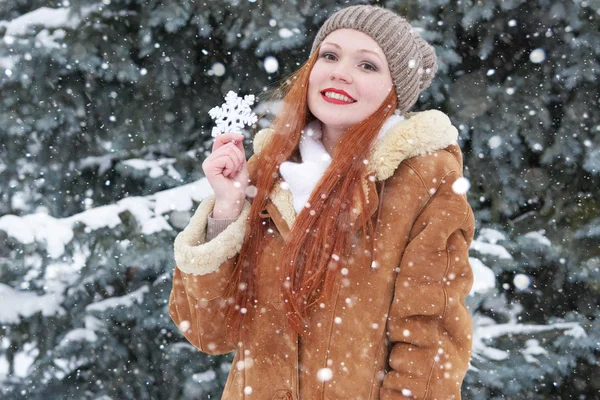 Retrato de niña en invierno al aire libre, clima nevado, mostrando gran juguete de copo de nieve . — Foto de Stock