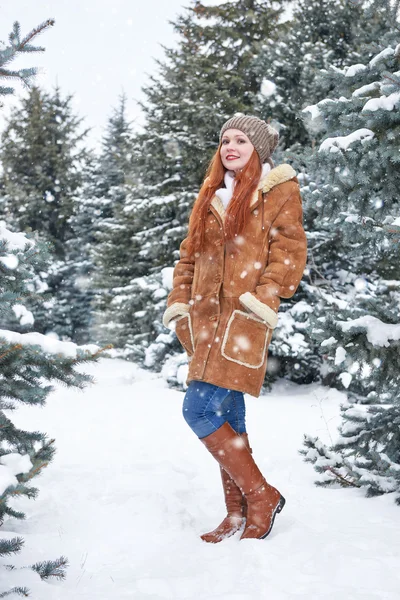 Chica en el parque de invierno por el día. Abeto con nieve. Pelirroja mujer longitud completa . — Foto de Stock