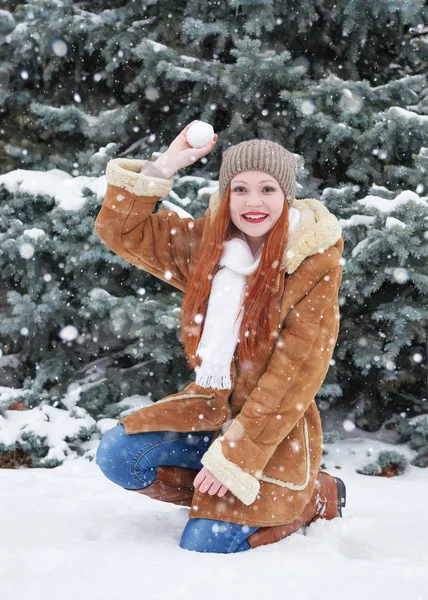 Girl play snowballs in winter park at day. Fir trees with snow. Redhead woman full length. — Stock Photo, Image