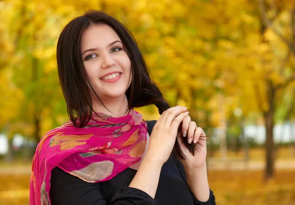 Beautiful girl in black dress and red scarf in yellow city park, fall season — Stock Photo, Image