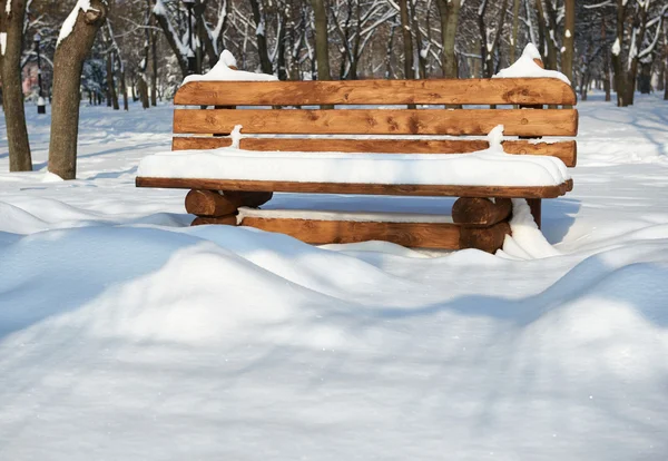 हिवाळी उद्यानात लाकडी खंडपीठ. उज्ज्वल सौर दिवस आणि बर्फ . — स्टॉक फोटो, इमेज