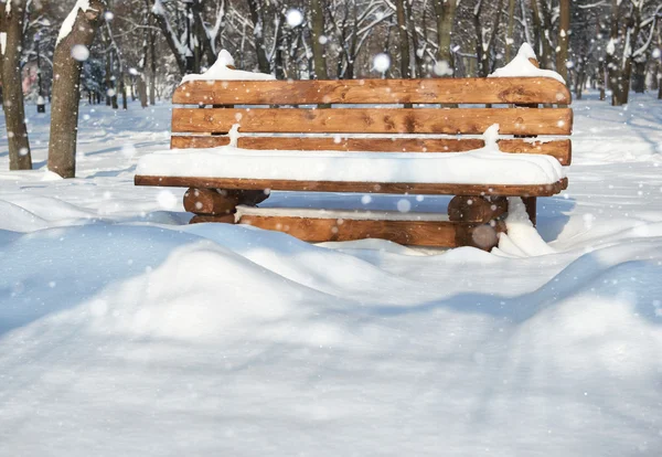 Banc en bois dans le parc d'hiver. Belle journée ensoleillée et neige . — Photo