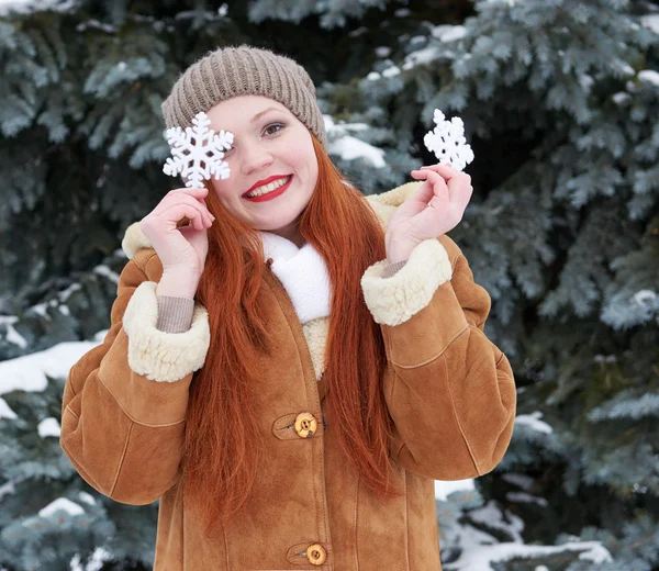 Retrato de niña en el bosque de invierno, clima nevado, mostrando gran juguete de copo de nieve . — Foto de Stock