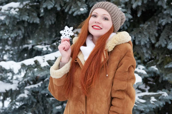 Girl portrait at winter outdoor, showing big snowflake toy. — Stock Photo, Image