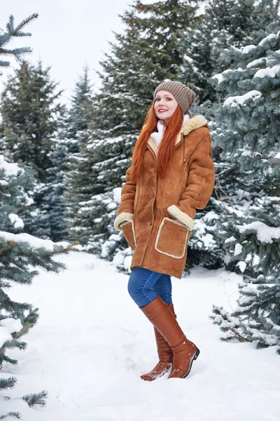 Girl in winter park at day. Fir trees with snow. Redhead woman full length. — Stock Photo, Image