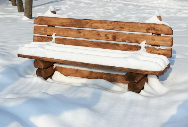 Wooden bench in the winter park. Bright sunny day and snow. — Stock Photo, Image