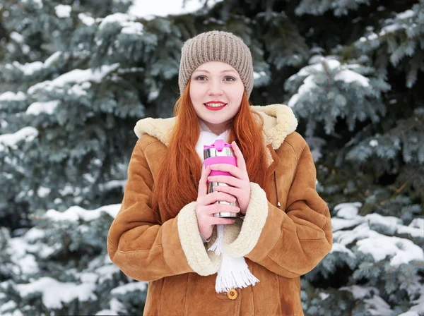 Lány kap meleg és ital tea téli parkban. Fenyők, a hó. — Stock Fotó