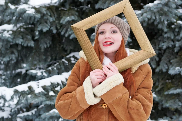 Portrait de femme dans un cadre photo en bois en hiver. Météo enneigée dans le parc des sapins . — Photo