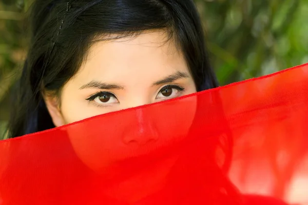 Vietnamese woman peeking over red fabric — Stock Photo, Image
