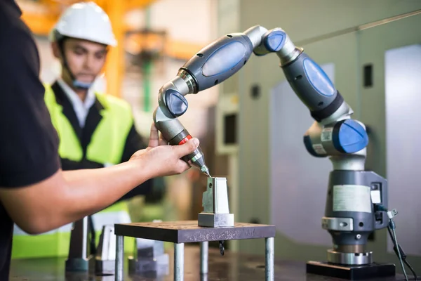 Factory worker hold robot hand arm to milling spare part metal equipment. Demonstate drilling lache position to inspector manager. Automation tool for high technology manufacturing.