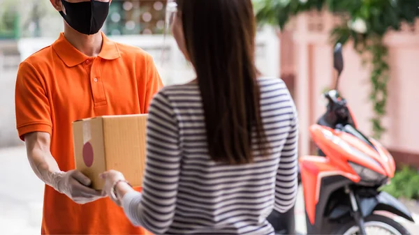 courier man deliver parcel to female customer with shield near delivery motorbike at home. Stay