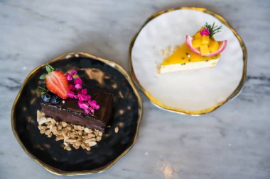Çilekli çikolatalı pasta ve çilekli meyveli cheesecake mable masada metin için fotokopi alanı. Çiçek süslemeli güzel bir tatlı..