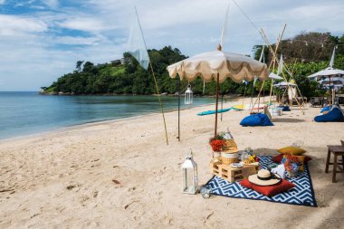 Plaj piknik paspası ve şemsiyeli aperatif, meyve, şampanya oteldeki süslü çiçekler, Phuket, Tayland. Yaz tatilinde öğleden sonra yiyip içiyorum..