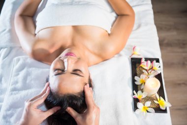 Tayland yağı kafa masajı, kaplıca salonundaki genç ve güzel Asyalı bayana tepeden bakıldığında. Ağrı konseptini iyileştirmek için sağlık ve rahatlama. Alternatif sağlık sektörü.