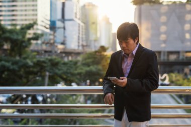 Asyalı Koreli CEO, 40 'lı yaşlarda ya da orta yaşlı bir adam, akıllı telefondan ofis binası dışında iş projesi planını tartışmak için mesaj atıyor. İletişim için şirket uygulamasını kullanıyor..