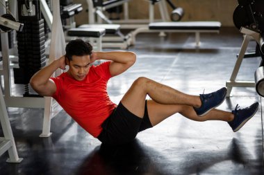Spor salonunda altı paket (üst ve alt karın kası ve kaslar) yapmak için bisiklet çatırdatan Asyalı sporcu kaslı adam. Vücut geliştirme, spor ve sağlıklı yaşam tarzı konsepti.