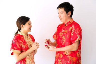 Kırmızı geleneksel Cheongsam kostümlü mutlu gülümseyen Çinli adam 2021 'de Çin' de yeni yıl teklifi için kız arkadaşına elmas yüzük verdi. Aşk ve evlilik kavramı.