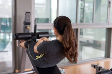 Sıska, genç, Asyalı bir kadın spor salonundaki egzersiz tezgahında mekik çekiyor. Spor vücut geliştirme ve sağlıklı yaşam tarzı konsepti.