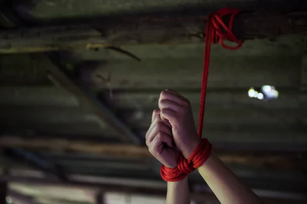 廃墟となった家の屋根の天井に赤いロープで縛られた被害者の手を閉じる 人質の概念か強盗から誘拐された女性 性的虐待レイプ犯罪 — ストック写真