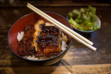 Unagi ızgara yılan balığı ve Japon sosu, una-don ve ahşap masada sebze salatası. Ünlü geleneksel Japon yemekleri..