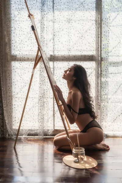 性感的亚洲女人在窗口用自然光完成绘画后 喜欢用水彩画在纸板上 艺术画廊的年轻艺术家女孩 图库图片