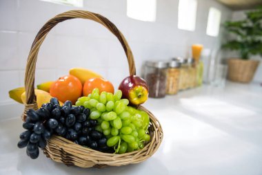 Meyve sepeti, portakal, elma, muz, mango. Mutfak tezgahındaki tahıl gevreği şişelerinin yanında. Sağlıklı beslenme tarzı.