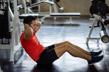 Asyalı atlet genç adam fitness salonunda karın kaslarını çalıştırarak (üst ve alt karın kasları ve eğiklikler) altı paket oluşturmak için oturur ve mekik çeker. Vücut geliştirme, spor ve sağlıklı yaşam tarzı konsepti.