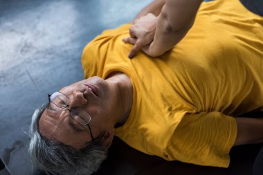 Yaşlı yaşlı adam fitness salonunda kardiyopulmoner resüsitasyon ya da kalp masajı (hayat kurtarma teknikleri) ile ilk yardım alır. 60 'lı yılların spor kulübünde geçirdiği kazada kalp krizi geçiren ya da sıcak çarpması semptomu gösteren emekli..