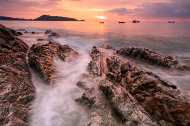 Gün batımında, Patong plajı yakınlarındaki Kalim sahilinde, Phuket, Tayland 'da, alacakaranlık gökyüzü ile birlikte, doğal taş kemerinde güzel bir deniz dalgası. Alacakaranlıkta uzun deniz manzarası. Tropikal bir ülkede yaz tatili için tatilci.