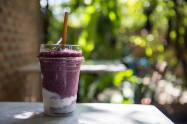 Açık kahve dükkanının bahçesinde, bulanık yapraklı bokeh ve tuğla duvar arkaplanlı meyveli yoğurt karışımı. Lezzetli, sağlıklı, içecek yaşam tarzı.