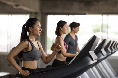 Group of young Asian friends running exercise on treadmills in sport fitness gym. Bodybuilding and Healthy sporty run on machine. workout, training, sport lifestyle concept.