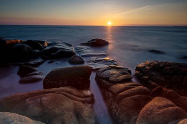 Seascape at sunset with motion sea waves through natural stone arch with light reflect on motion water at Larn Hin Kaw, Rayong, Thailand. Famous travel destination or holiday maker in tropical country