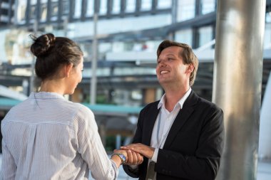 Resmi üniformalı gülümseyen Amerikalı işadamı iş kadınıyla el sıkışıyor. Şehir merkezindeki proje tartışmasından önce merhaba demek için..