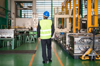 Üretim bölümündeki modern makineleri kontrol etmek için kasketli fabrika müdürünün arkası. Sanayi sektörü konsepti.