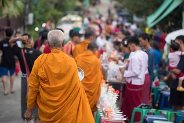 Yaşlı keşiş, Mon halkının sadakalarına ve Sangkhla Buri köyü, Kanchanaburi, Tayland 'a çok sayıda ziyaretçiye yürüyor. Meşhur seyahat aktivitesi sabahları yemeği hak etmek içindir..