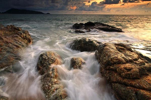 Хвиля з скелястим пляжем в сутінках — стокове фото
