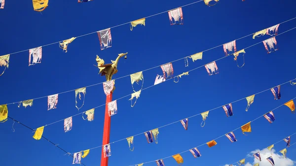 Estátua de pássaro dourado no pólo vermelho com bandeiras tailandesas — Fotografia de Stock