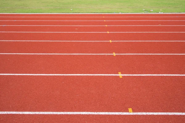 Rode atletiekbaan met groen gras — Stockfoto