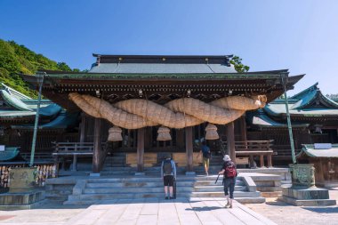 Turistler Miyajidake Tapınağı 'nı ziyaret ediyor. Shimenawa' nın en büyük ipleri, mavi gökyüzü, Fukutsu, Fukuoka, Japonya 'nın ana tapınağının girişinde asılı. Meşhur seyahat yeri.
