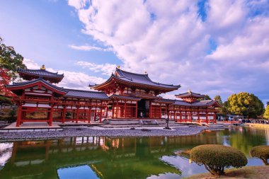 Kızıl Anka Salonu 'ndaki Byodo-In tapınağında sonbaharda akçaağaç yaprağı renkleri ve ufuk çizgisi yansıması olan insanlar, Uji, Kyoto, Japonya. Aralık ayında Kansai 'de turistler için ünlü bir tatil beldesi.