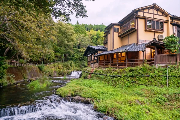 Japonya 'nın Kumamoto şehrinde, Kurokawa' daki Ryokan Otel binalarının yanında çağlayarak akan nehir ve doğal kaya. Kyushu 'daki cennet gibi sıcak bahar kasabasının ünlü seyahat yeri..